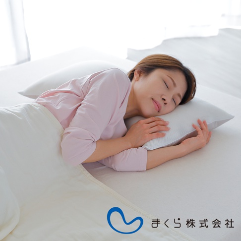 一位女性側臥，頭部枕於一個白色、帶有細微織紋的低枕上，身蓋白色床單。