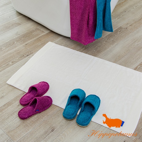 一對紫色和一對藍色的竹棉混紡室內拖鞋，放置在白色地墊上。