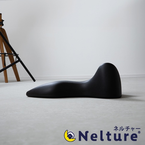 黑色肩頸背拉伸牽引枕，呈流線型設計，具有人體工學曲線，可支撐頸部和背部，材質為柔軟且有彈性的合成材料。