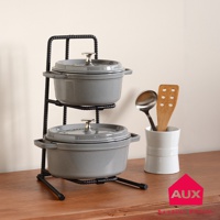 黑色金屬工業風兩層收納展示架，架上擺放兩個灰色鑄鐵鍋，鍋蓋中央有銀色把手。右側有白色陶瓷杯，杯內插著一個不鏽鋼湯勺和一個木質鍋鏟。