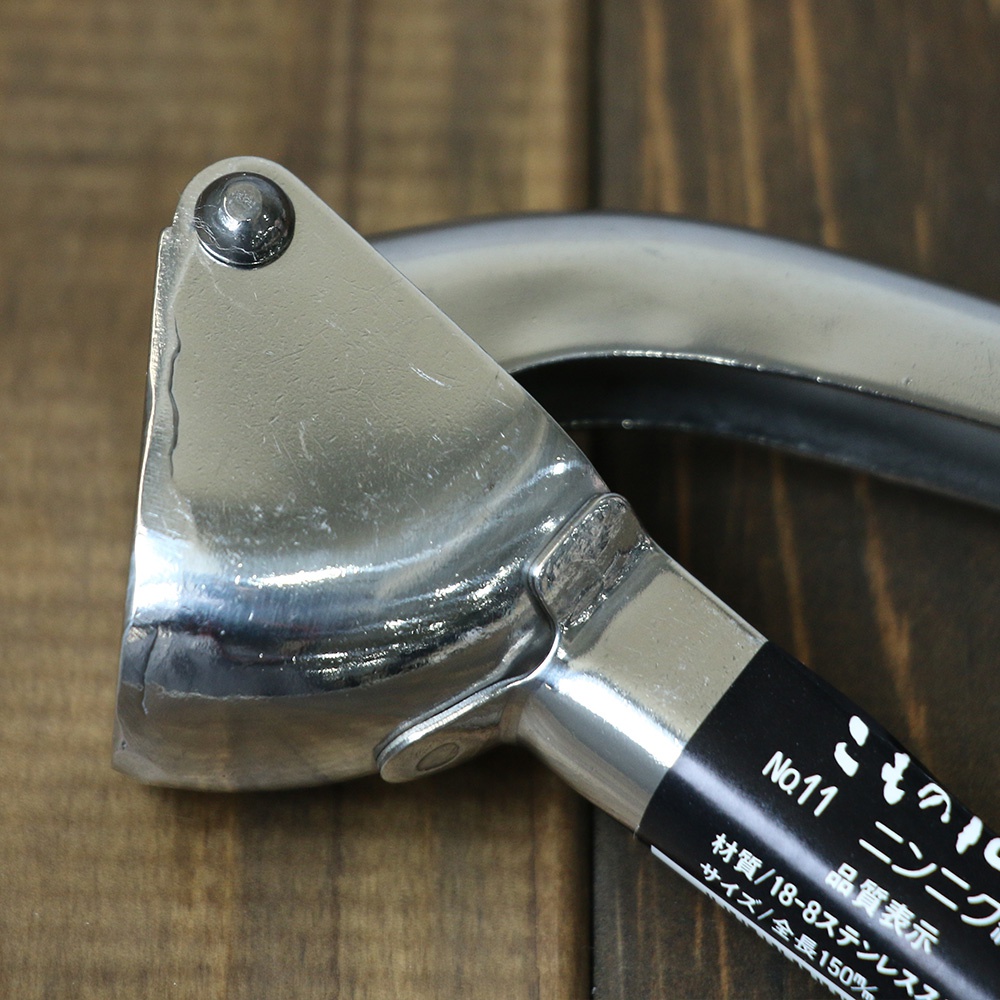 不鏽鋼壓蒜器，銀色，由金屬製成，帶有黑色標籤，上面印有日文文字。