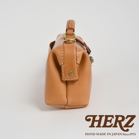 HERZ 職人手作橫長形杜勒斯單肩包，焦糖色皮革，經典醫生包造型，細節處有黃銅色五金與手工縫線，標示 HAND MADE IN JAPAN Since1973