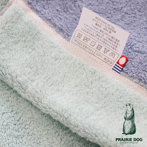 今治純棉雙股紗單人毯，一面為淺綠色，一面為淺藍色，材質標籤顯示 100% 純棉，尺寸為 140x190cm。