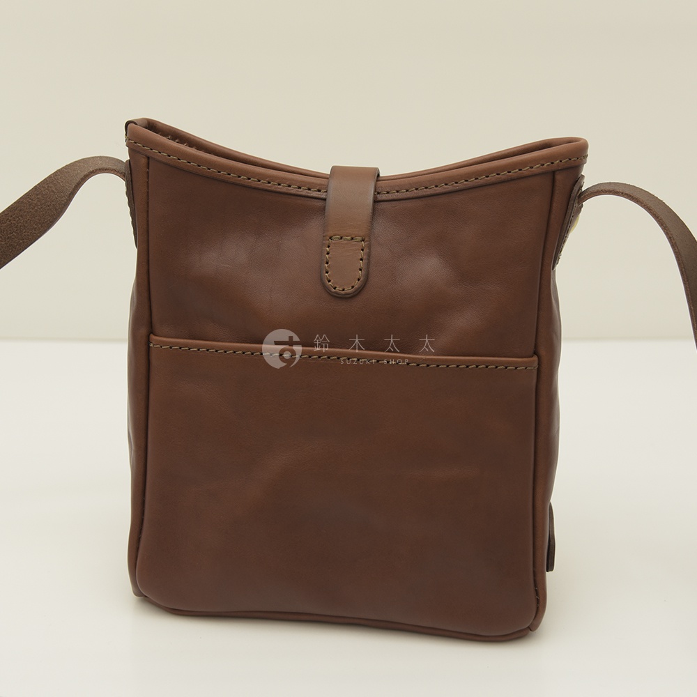 深棕色職人手作皮革輕便單肩側背包，正面有平整的口袋和皮革搭扣，搭配同色系皮革背帶。