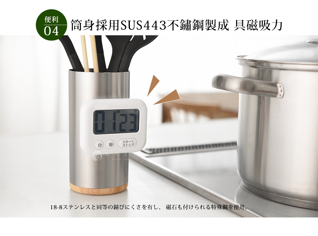 逸品物創不鏽鋼餐具收納筒，為SUS443不鏽鋼製成，筒身呈現銀色金屬光澤，底部帶有木紋色澤的圓形底座。收納筒內裝有多支不同材質的廚房用具，如鍋鏟、夾子等。筒身旁吸附一個白色方形電子計時器，顯示數字「0123」，下方有中日文按鈕。