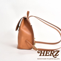 職人手作皮革翻蓋迷你後背包，呈現自然棕色調，以優質皮革製作，設有可調節肩帶和金屬扣件，設計簡約實用。