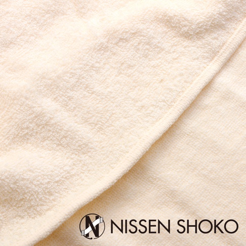 米白色毛巾布質地的枕套，織紋清晰，材質柔軟，邊緣有車縫線，右下角有「NISSEN SHOKO」品牌標誌。