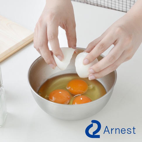 Arnest 防刮不鏽鋼調理碗，特寫鏡頭顯示雙手正在打雞蛋，準備放入碗中，碗裡有三顆蛋黃。