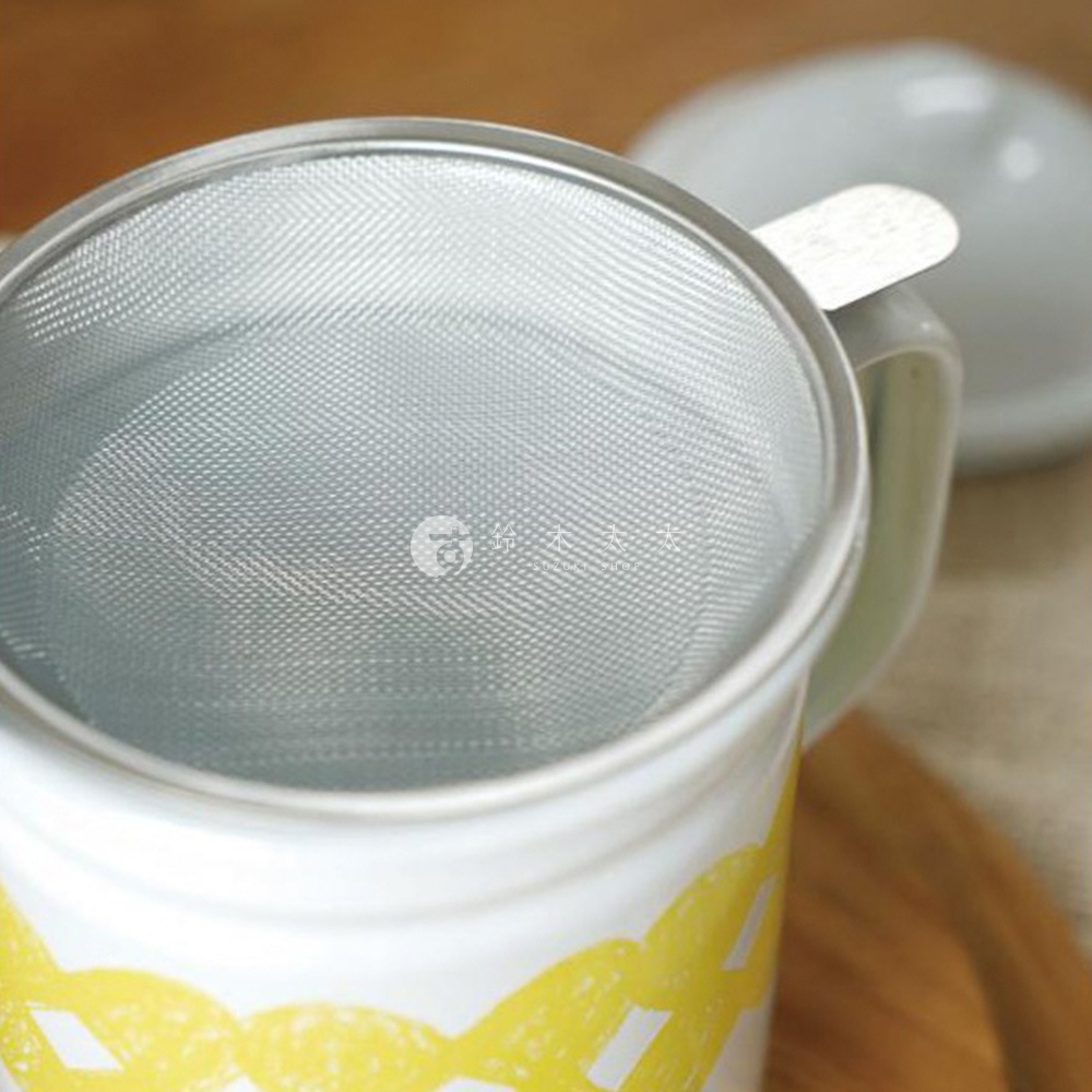 白色琺瑯濾油壺，壺身飾有黃色網狀圖案，壺口內嵌金屬濾網，附有白色壺蓋。