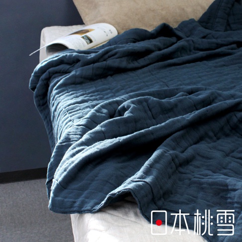 深藍色八層紗雙人透氣被，材質輕柔，紋理細緻，覆蓋在床上，一角有雜誌。