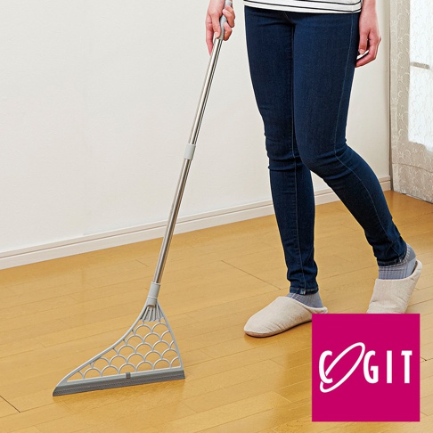 銀色金屬桿連接灰色三角形掃頭，掃頭上有魚鱗狀紋路，底部為灰色橡膠刮條，用於清潔地板。