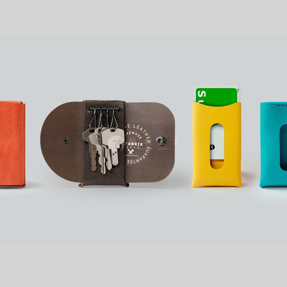兩個皮質鑰匙包，一個棕色，上面有幾把鑰匙，另一個黃色，裡面插著一張卡片。