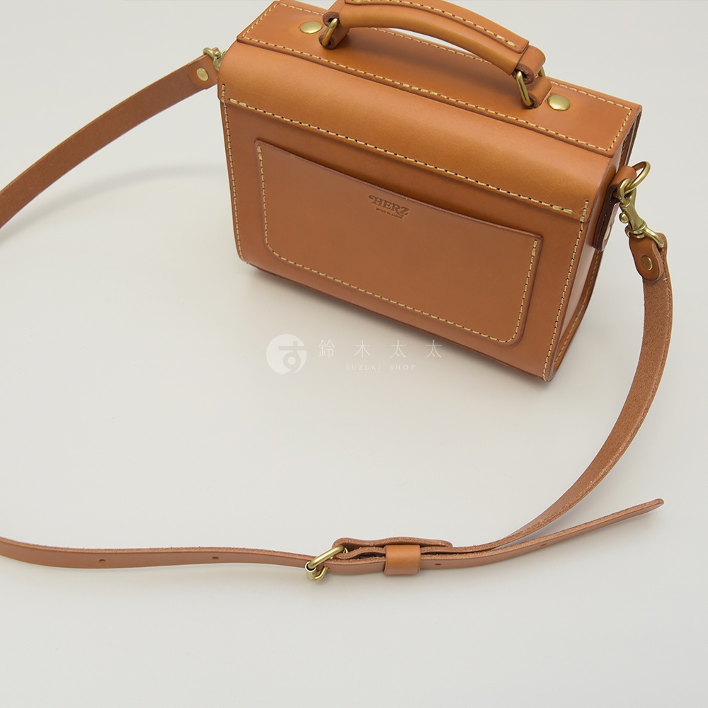 職人手作咖啡色皮革極簡風兩用迷你包，設有提把及可拆卸肩帶，包身前方有方形貼袋，搭配金色五金配件。