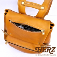 職人手作皮革多口袋後背包 R-135，採用溫暖的焦糖棕色牛皮製成，設有多個拉鍊口袋，展現精緻縫線與質感。