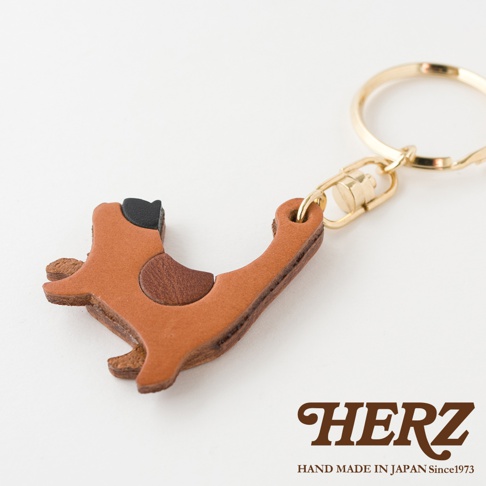 職人手作皮革貓咪造型鑰匙圈，主體為棕色皮革，耳朵和斑點為黑色及深棕色皮革拼接，搭配金色金屬掛環。