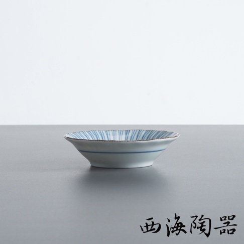 一個白底藍線條紋的陶瓷小碟，邊緣呈波浪狀。