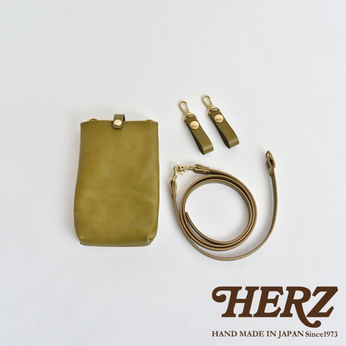 橄欖綠色皮革手機包，附有兩條可拆卸的皮革掛繩，一條較長可斜背，兩條較短附有金色鉤扣。