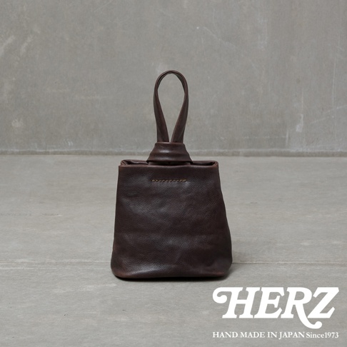 職人手作皮革Organ單柄手提包，深棕色，採用柔軟皮革製作，包身方形，頂部有單個提把，提把處以皮革繩結設計，包身縫線明顯，整體風格簡約。