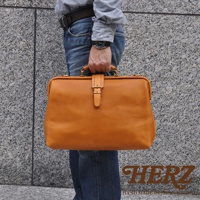 職人手作皮革軟式杜勒斯包，呈現溫潤的駝色，以高品質皮革製作，搭配金屬釦環與提把，展現簡約質感，適合日常攜帶。