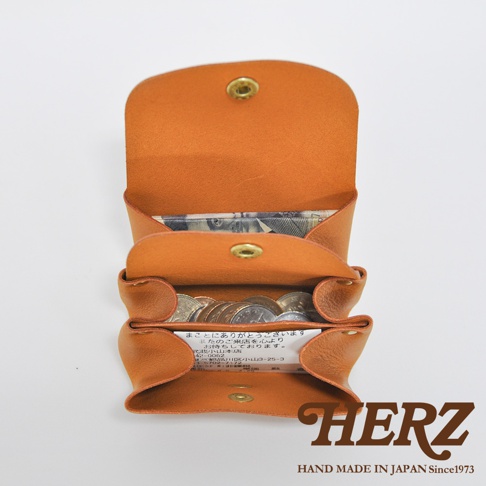 職人手作皮革三層收納零錢包，呈獻溫暖的棕褐色，其三層結構可清晰收納紙鈔與硬幣，整體散發天然皮革的質感，並以金屬釦固定。