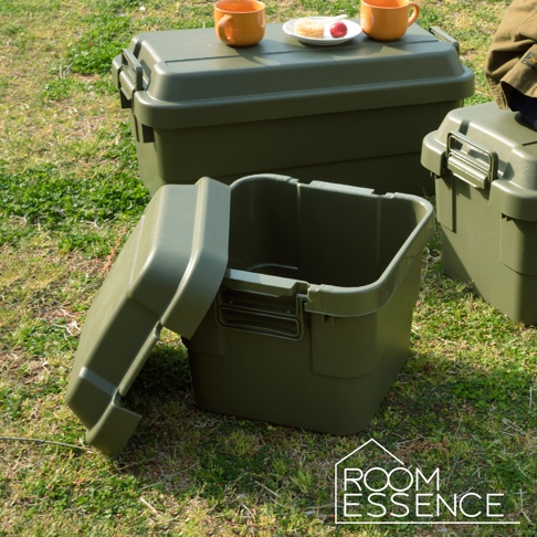 軍綠色高強度方形收納箱，其中一個箱子打開著，露出內部空間，箱子採用厚實的塑膠材質，帶有卡扣式提把設計，擺放在草地上。