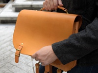 職人手作皮革雙扣三用後背包 (CW-137) MH，以溫暖的橘棕色天然皮革製成，設計簡潔，帶有可調節的皮帶扣和金屬五金配件，展現經典復古風格。