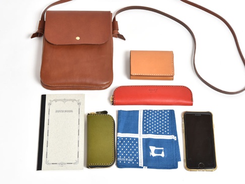 職人手作皮革橫式隨行袋 (CP-9) 為棕色皮革材質，設計簡約，附有可調節式長背帶，另有卡夾、筆袋、筆記本、鑰匙包、手帕及手機等配件。