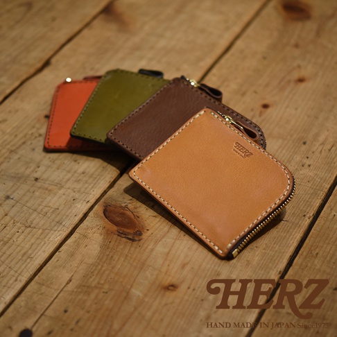 職人手作皮革L型拉鍊迷你短夾，展現多種顏色，包含橘色、橄欖綠、咖啡色及淺棕色，皆為皮革材質，拉鍊處有金色五金。