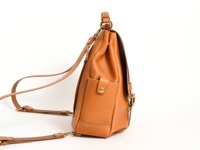 棕褐色皮革雙扣後背包，側面有方形口袋，配有可調式細肩帶和頂部提把，整體呈現簡約風格。