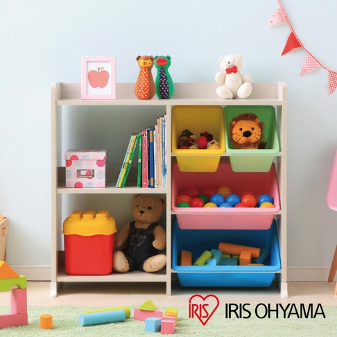 白色木製兒童玩具書櫃收納架，設有四層，頂層擺放著裝飾品、玩偶，中間三層為不同顏色的收納盒，分別裝有玩具、書籍和軟球，底部一層則擺放著大型積木玩具和泰迪熊玩偶。