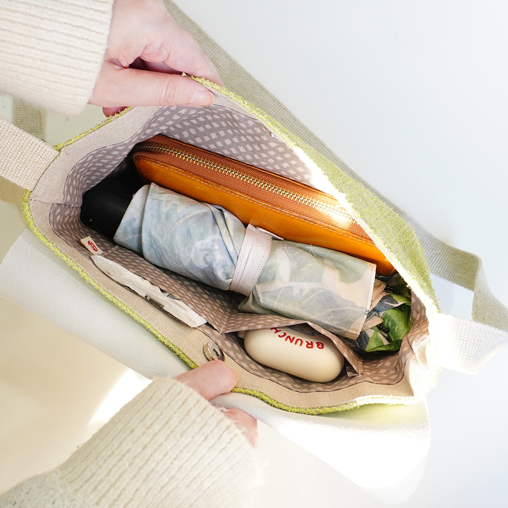 BAN INOUE 品牌，蚊帳棉裂織手提袋，可見袋內有橘色拉鍊皮夾、摺疊傘、肥皂。