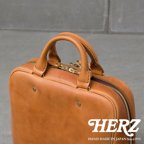 HERZ 商標，手工製作的日本皮革後背包，具有雙提把和拉鍊開合。