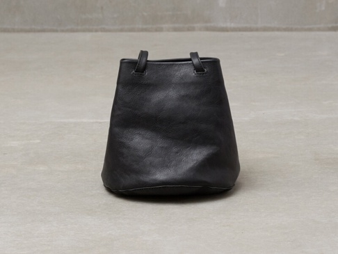 黑色皮革抽繩水桶包，帶有兩個短提把，可肩背或手提。