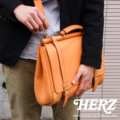 日本HERZ職人手作皮革屋瓦風側背包，由雙手製作，使用天然皮革，呈現溫暖的焦糖色調，金屬釦件閃耀著復古光澤。
