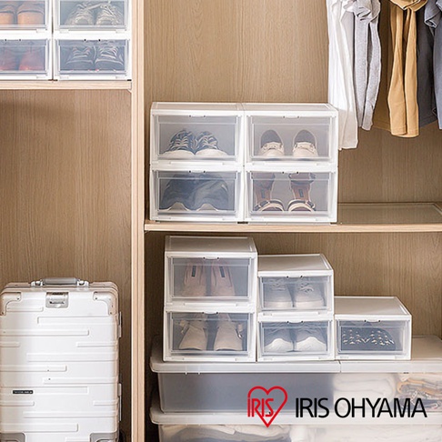 展示了多個日本IRIS OHYAMA品牌4入透明收納鞋盒，鞋盒為方形設計，搭配白色邊框和透明面板，內部收納有各式男女鞋款，整齊擺放在木紋衣櫃的層架上，一旁還有銀色行李箱。