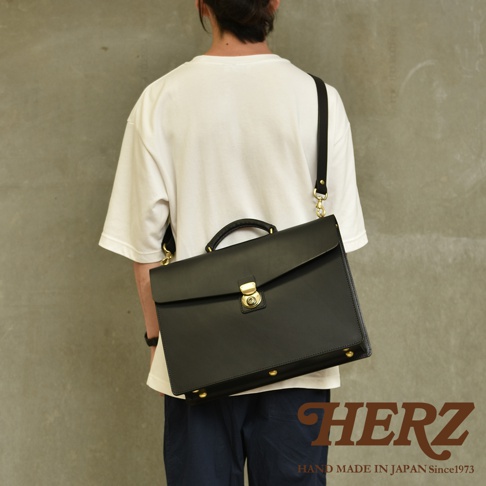 職人手作黑色皮革Organ兩用商務公事包，配有金色鎖扣和金屬配件，可肩背或手提。