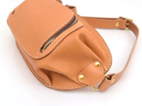 職人手作皮革拉鍊旅行斜背包 (F-7) 是一款棕褐色全皮革製成的斜背包，配有黃銅色拉鍊、縫線細節和可調節式皮革背帶，適合旅行使用。