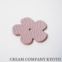 粉色皮革製成的五瓣花形吊飾，帶有細緻紋理，中央有一個小孔。