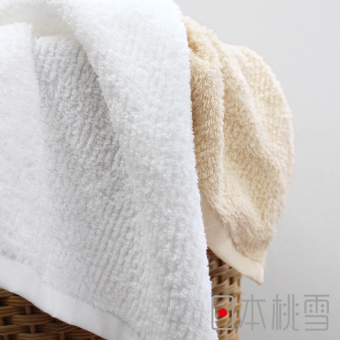 兩條今治細絨浴巾，一條為純白色，另一條為淺米色，質地柔軟蓬鬆，呈現細膩的絨毛感，疊放在藤編籃中。