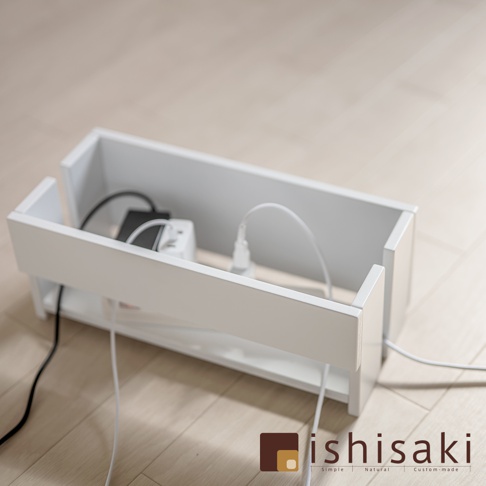 白色木質電線收納盒，內部放置有延長線、插座及多條黑色和白色電線。收納盒設計簡潔，兩側有開口便於電線穿出。