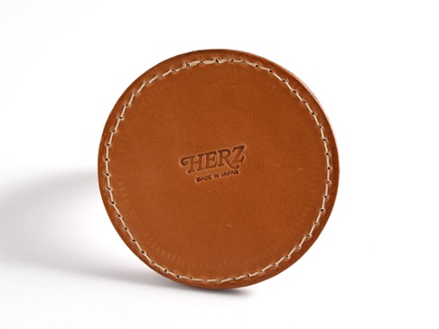 職人手作皮革兩入用筆架，採用棕色皮革製成，圓形設計，邊緣以白色縫線加固，頂部壓印有「HERZ」品牌標誌及「MADE IN JAPAN」字樣。