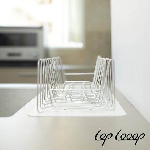 銀色不鏽鋼線條編織而成的伸縮式瀝水架，可折疊收納，帶有白色防水墊。