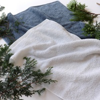 兩條精梳棉迷你浴巾，一條為純白色，另一條為淺灰色，皆有檜木綠葉裝飾。