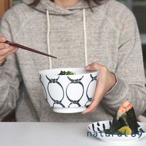 白色陶瓷丼碗，飾有黑色網格狀手繪圖案，碗內盛有食物，由手持筷子的人端著。
