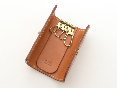 職人手作經典鑰匙包，採用棕色皮革製成，內有四個金色金屬鉤，皮革上有品牌壓印。