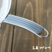 不鏽鋼濾網的銀色金屬握柄，覆蓋著灰色防滑矽膠，握柄上有橫向凹槽設計，末端為環形。