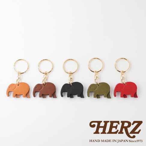五個皮革大象造型鑰匙圈，顏色分別為：橘色、咖啡色、黑色、軍綠色、紅色。每個鑰匙圈都附有金色鑰匙環。