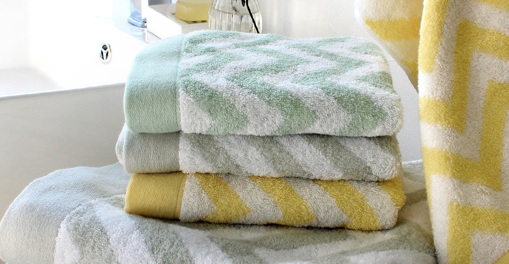 堆疊的毛巾，有淺綠色、灰色和黃色條紋圖案，放在浴室裡。