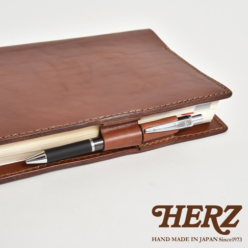 一個帶筆的棕色皮革筆記本封套，封套上有HERZ LOGO