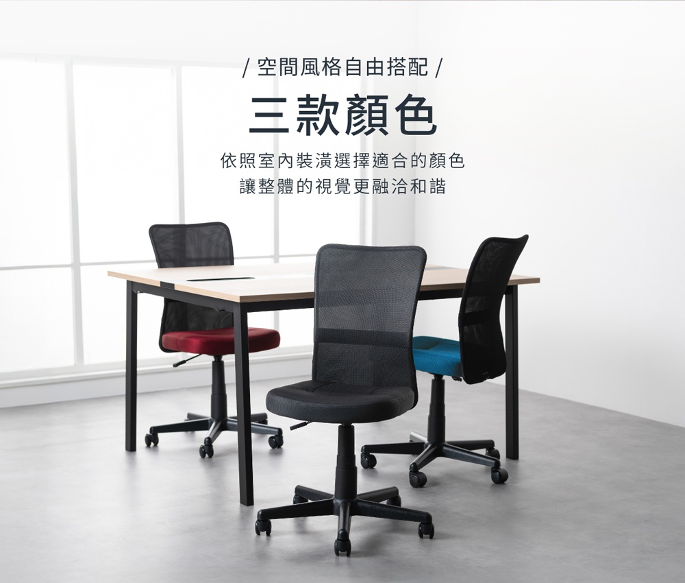 一間現代辦公室裡，一張木質桌面搭配黑色金屬桌腳的長方形辦公桌，桌上有三個網布辦公椅，分別是紅色、藍色和黑色，椅背和坐墊皆為黑色網布材質，有滾輪底座。